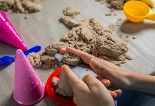 Close up van handen die met zand en een schep spelen