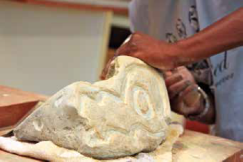 Een Afrikaanse jongen beitelt een steen