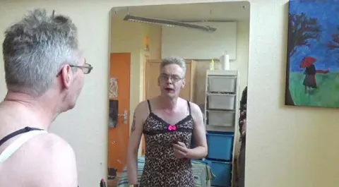 man in jurk kijkt in spiegel