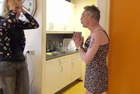 Man in jurk praat met vrouw met handen in haar